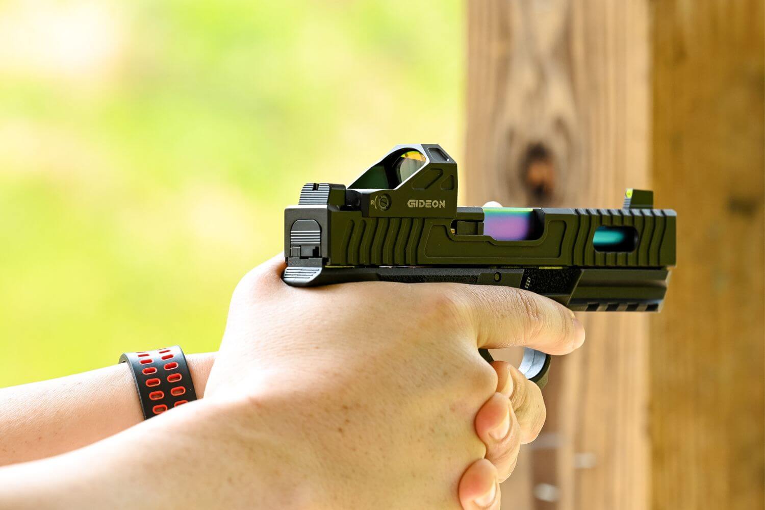 Man aiming a firearm with custom upgrades at an outdoor shooting range